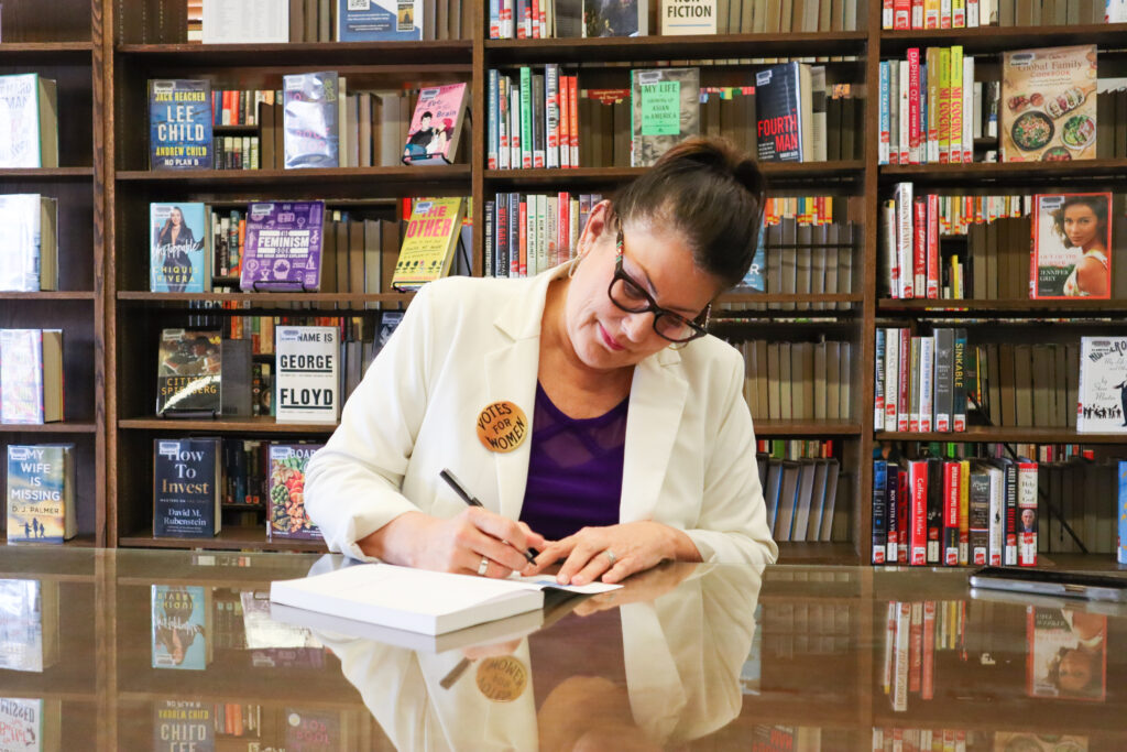 Vice Mayor Cindy Allen signing a copy of The Hungry Heart: A Woman's Fast for Justice by Zoe Ann Nicholson inside the Alamitos Branch Library in Long Beach